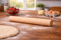 Wooden rolling pin on a wooden table with flour, dough, and kitchen items in the background.