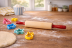 Rolling pin with colorful cookie cutters on a wooden surface with flour.