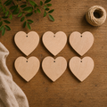 Set of six wooden heart-shaped tags on a wooden surface with twine and leaves.