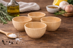 Set of wooden bowls on a wooden surface with various ingredients around them.