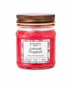 Red candle in a mason jar with a brown lid on a white background