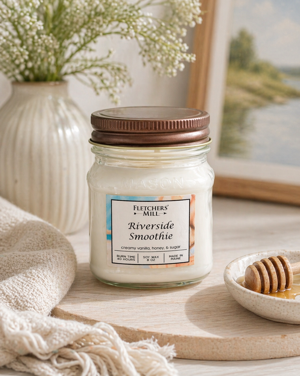 Jar of 'Riverside Smoothie' candle from Fletchers Mill on a table with decorative items.